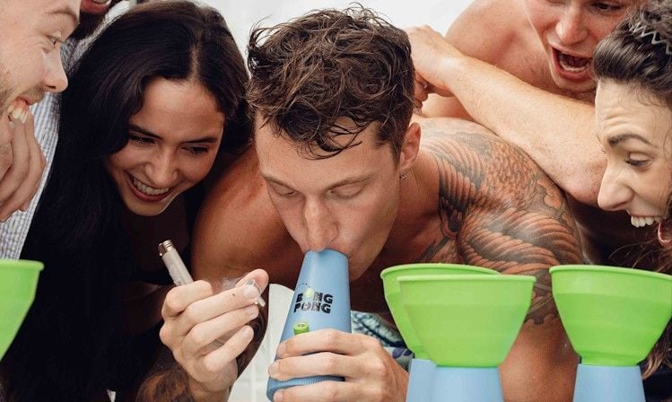 Friends crowding around a table playing Bong Pong
